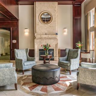A luxurious lobby featuring elegant armchairs arranged around a circular table, centered by a fireplace with modern decor.