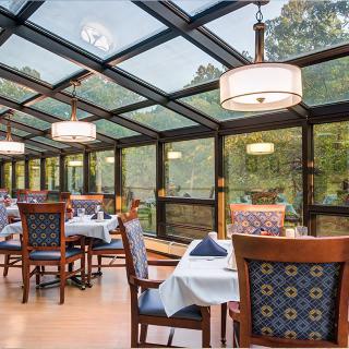 An elegant dining area with a glass ceiling and forest views.