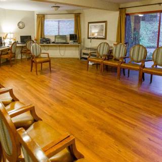 An empty waiting room with multiple chairs and a wooden floor.