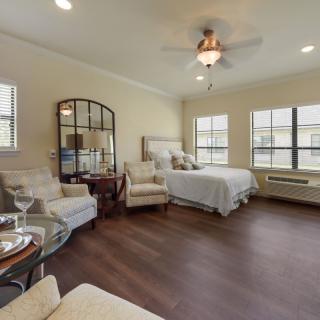 A spacious bedroom with elegant decor, featuring a comfortable bed, armchairs, and large windows that allow natural light to fill the room.