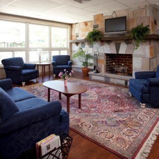 A cozy living room featuring blue chairs, a fireplace, and a television.