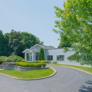A beautifully landscaped residential property featuring a modern house surrounded by lush greenery.