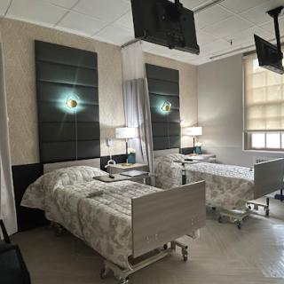 A well-lit hospital patient room featuring two beds and modern furnishings.