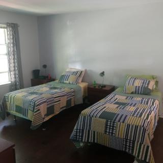A bedroom with two twin beds featuring quilted bedspreads, nightstands, and a window providing natural light.
