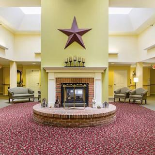 A welcoming lobby interior featuring a central fireplace with a large star decoration above, surrounded by comfortable seating and patterned carpet.