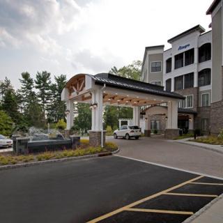 A hotel's entrance featuring a covered driveway and landscaped surroundings.