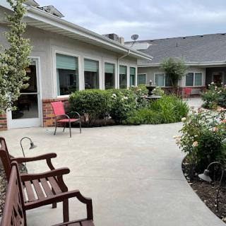 A serene courtyard featuring a winding pathway, benches, and lush greenery.
