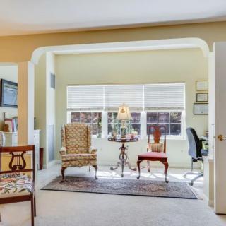A cozy living area featuring classic armchairs, a desk setup by the window, and elegant decor elements.