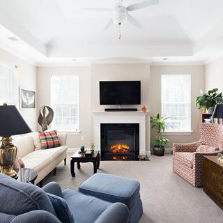 A cozy living room with a fireplace, comfortable seating, and a television mounted above.