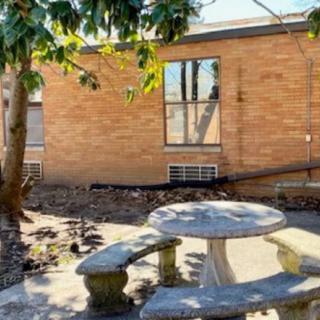 A serene outdoor patio area with a stone table and benches, set against a brick wall.
