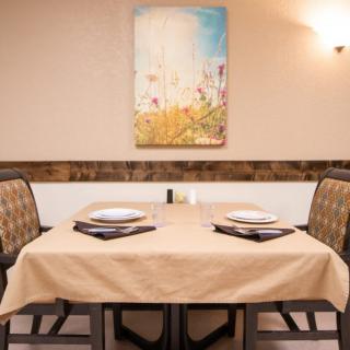 A neatly set dining table in a restaurant, featuring simple decor and artwork on the wall.