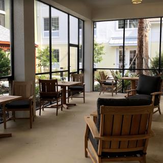 A cozy indoor seating area with tables and chairs, surrounded by large windows letting in natural light.