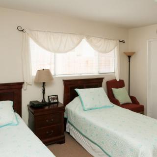 A cozy bedroom with twin beds and a lamp by the window.
