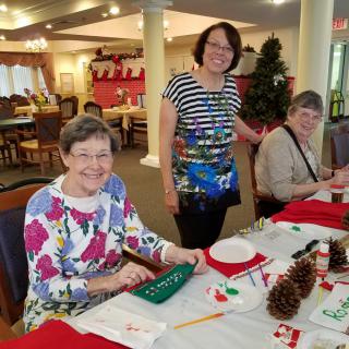 A group of people engaged in a crafting activity with holiday decorations on the table.