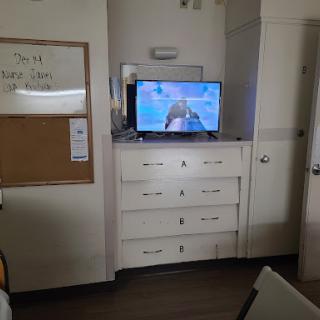 A view of a room featuring a television mounted above a dresser.