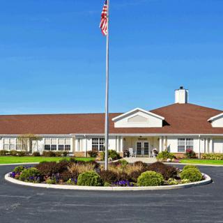 A one-story building with an American flag in front, surrounded by a landscaped circular driveway.