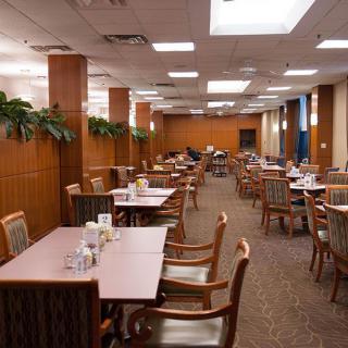 An empty dining room with neatly arranged tables and chairs, featuring warm lighting and wall decorations.