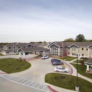 A residential building with a parking lot and several parked vehicles in a suburban area.