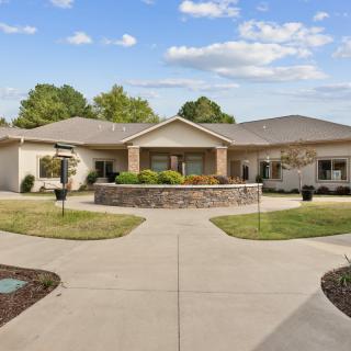 A suburban house with a circular driveway and landscaped front yard.