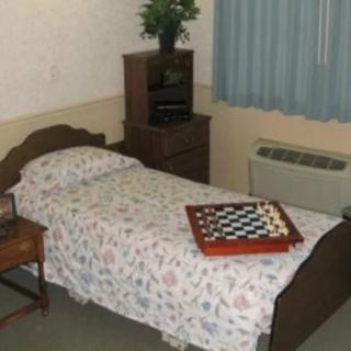 A small bedroom with a single bed and a checkers board on top.