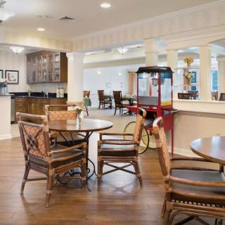 A cozy dining area with wooden furniture, a kitchen in the background, and a bright red popcorn machine.