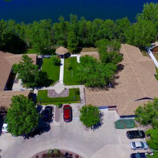 A serene aerial view of a residential community by the lake, surrounded by lush greenery.