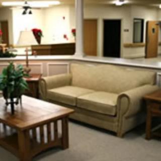 A cozy living room with a beige sofa, wooden coffee table, and decorative plants.