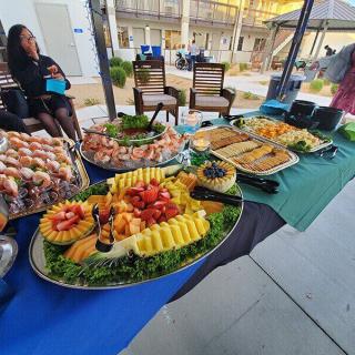 A well-organized buffet spread at an outdoor event featuring various fruit platters and other dishes.