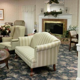 A cozy living room with classic furniture and a fireplace, featuring a patterned carpet and elegant decor.