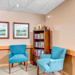 Cozy waiting area with two blue chairs and a bookshelf.
