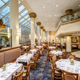 An elegant restaurant interior with neatly arranged tables under a large skylight.