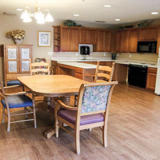 A spacious kitchen with wooden cabinets, a dining table, and chairs on a wooden floor.