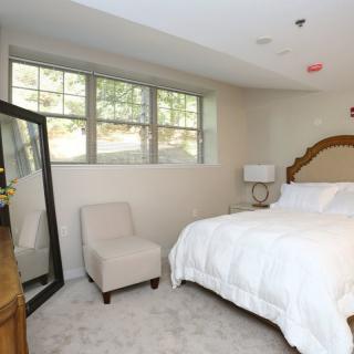 A cozy bedroom with a large bed, standing mirror, and soft carpeting.