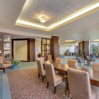 A modern office space with a large conference table surrounded by chairs, featuring warm lighting and contemporary decor.