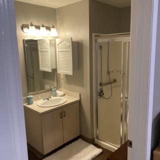 A well-lit bathroom with a vanity sink, mirror, and shower enclosure.