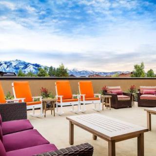 A vibrant patio with colorful seating offers a scenic view of mountains under a blue sky.