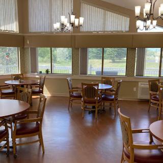 A spacious and well-lit dining area featuring wooden tables and chairs, with large windows that allow natural light to fill the room.
