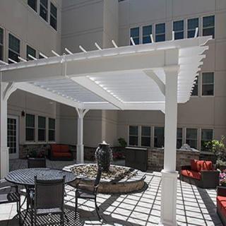 A courtyard with a white pergola providing shade over outdoor seating and patio furniture.