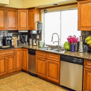 A modern kitchen with wooden cabinets, a variety of appliances, and a window over the sink.