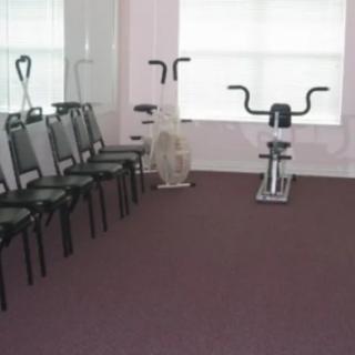 A small exercise room featuring a few chairs and two stationary bikes.