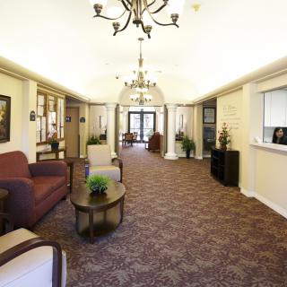 A spacious lobby with elegant chandeliers, comfortable seating, and a carpeted floor.