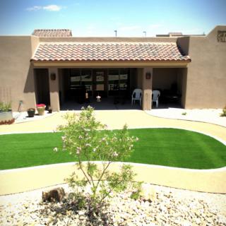 A southwestern-style house with a desert landscape and artificial turf in the yard.