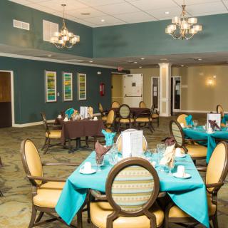 An elegant dining room with turquoise table settings and chandeliers.