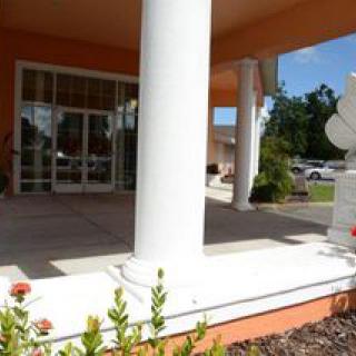 An elegant entrance with white columns and a landscaped patio area.