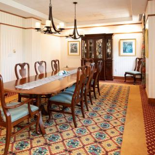 Elegant dining room with a long table, chairs, and chandeliers.