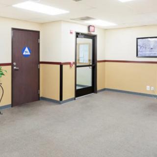 An empty office waiting area with a carpeted floor and doors leading to other rooms.