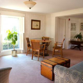 A cozy living and dining area with wooden furniture and a large window allowing natural light.
