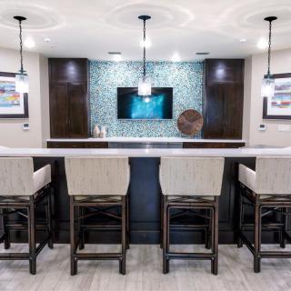 A modern home bar with a sleek countertop, pendant lighting, and stylish seating.