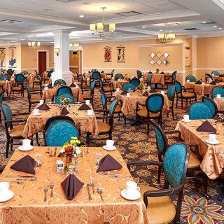 An elegantly set dining room with multiple tables and chairs ready for guests.