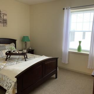 A cozy bedroom with a bed, bedside lamp, and window with curtains.